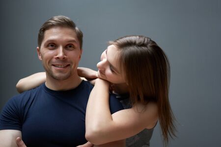 Hugging man and woman against gray wallの写真素材