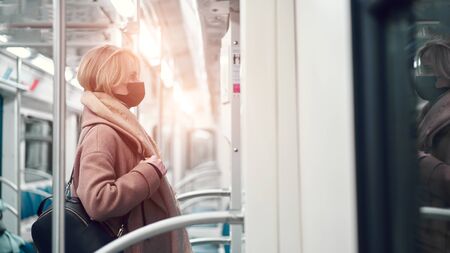 Young woman in black medical mask standing in subway near carriage.の写真素材