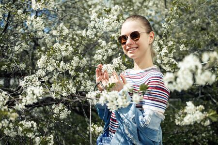 Happy woman in sunglasses on background of blossoming apple treeの写真素材