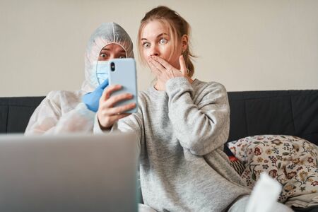 Surprised woman and man in protective suit next to laptops in apartmentの写真素材