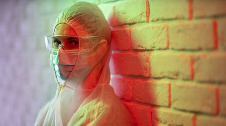 Doctor in protective suit on background of brick wall in red zone.の写真素材