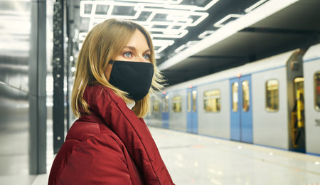 Woman in mask and red coat in the subway