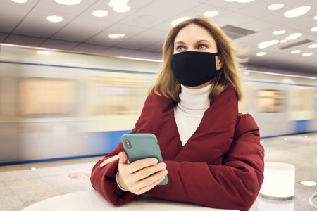 girl in a mask holds a phone in her hands