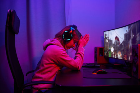 Young gamer girl sitting at pc in neon led ligthsの写真素材
