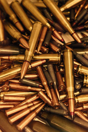Pile of bullets with copper tips under a warm light. Close up of a lot of bullets. Gun violence in America. Ammunition rifle or pistol. tonedの写真素材