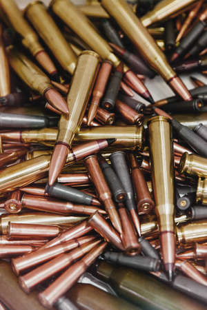 Pile of bullets with copper tips under a warm light. Close up of a lot of bullets. Gun violence in America. Ammunition rifle or pistol.の写真素材