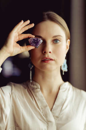 Young european girl holding a gemstone in hand in front of her. Looking towards the camera. Mystical woman..の写真素材