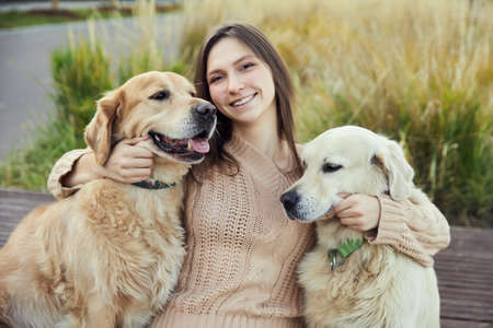 beautiful girl hugs two golden retrievers. Outdoorの写真素材