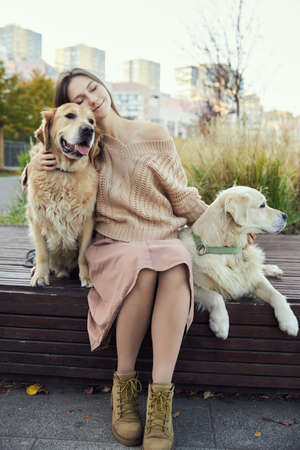 beautiful girl hugs two golden retrievers. Outdoorの写真素材