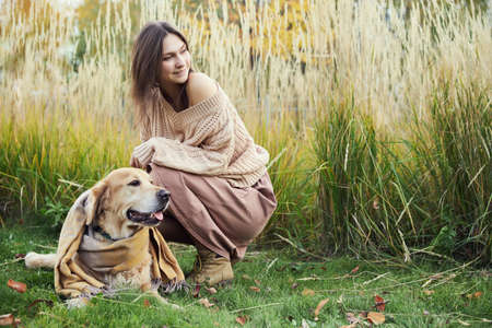Beautiful girl with two golden retrievers in parkの写真素材