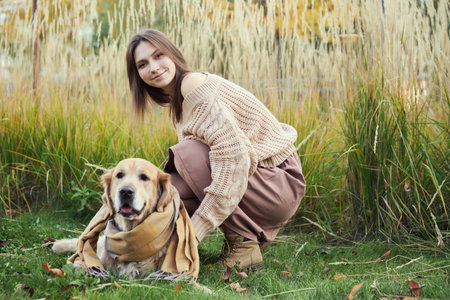 Beautiful girl with two golden retrievers in parkの写真素材