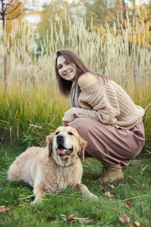 Beautiful girl with two golden retrievers in parkの写真素材