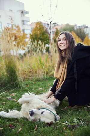 Beautiful girl with golden retriever in parkの写真素材