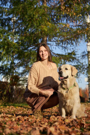 Beautiful girl with golden retriever in parkの写真素材