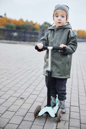 boy ride a scooter along the embankmentの写真素材