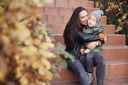 beautiful girl sitting on the stairs and holding her babyの写真素材
