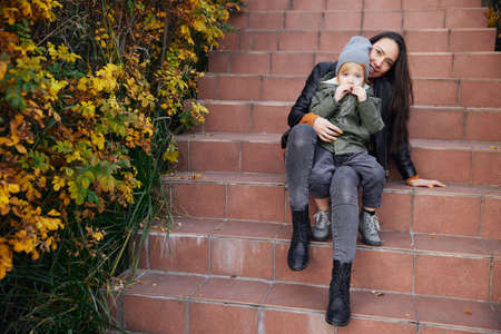 beautiful girl sitting on the stairs and holding her babyの写真素材