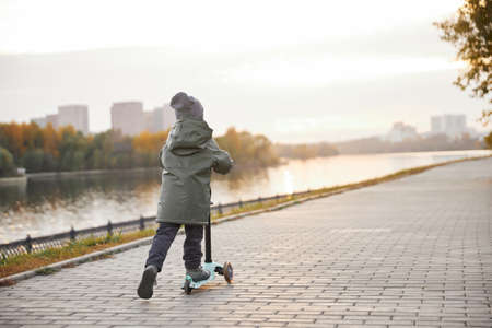 boy ride a scooter along the embankmentの写真素材