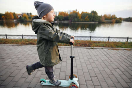 boy ride a scooter along the embankmentの写真素材