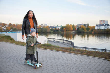 beautiful girl teaches her child to ride a scooterの写真素材