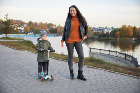 beautiful girl teaches her child to ride a scooterの写真素材