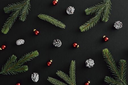 Christmas minimal concept - silver and red bauble and evergreen tree branch on dark background. Holiday concept. Winter holiday glitz decor. Trendy design.の写真素材