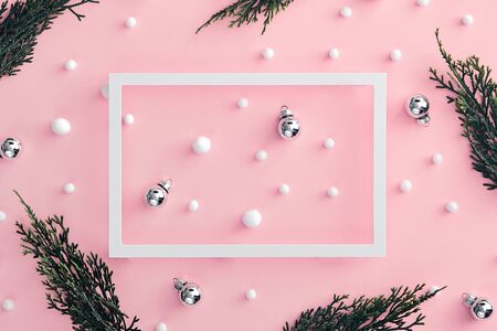 Christmas minimal concept - composition with christmas bauble, tree branch and snowball on pink background. White paper frame. Winter xmas snow background. Minimal holiday concept. Holiday mockup.の写真素材