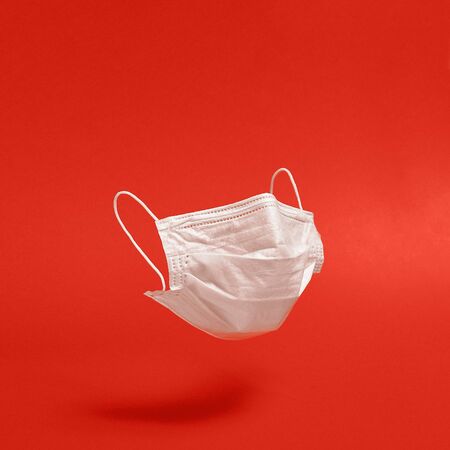 Surgical face mask on red background. Minimal medical concept. Medical equipmentの写真素材
