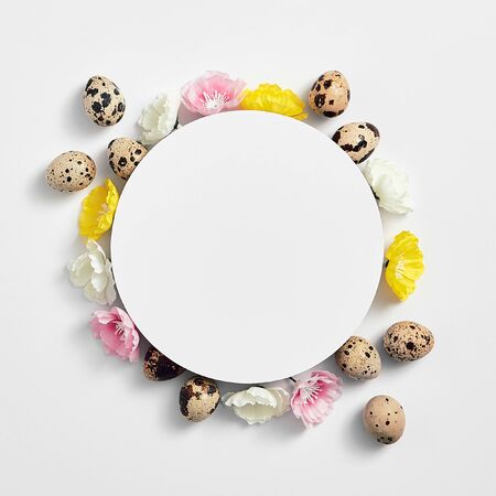 Spring minimal concept. Creative easter flat lay with paper blank. Quail eggs with flower top view. White background.の写真素材