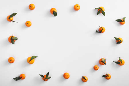 Ripe tangerines on white background top view. Flat lay with tasty oranges. Citruces with green leaves. Food composition with exotic fruits. Vegetarian dessert. Sweet mandarin frame with copyspaceの写真素材