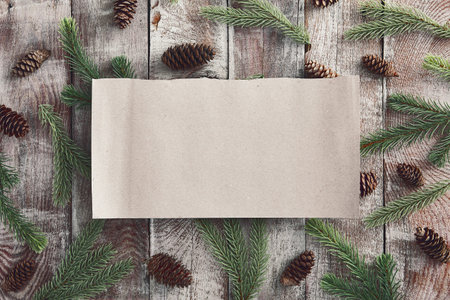Old wooden table background with blank space. Winter season frame. Torn parchment piece. Fir tree...