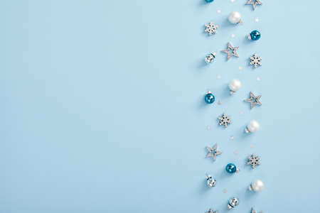 Christmas minimal mockup - white, glass and blue balls, snowflakes and stars confetti on blue background. Horizontal composition, flat lay, top view. Light blue background. Winter backdrop.の写真素材