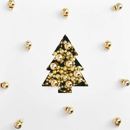 Christmas minimal layout - shape of christmas tree made of golden garland and bauble. Square composition, flat lay, top view. Christmas holiday mockup on white background.の写真素材