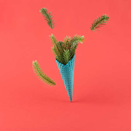 Ice cream cone with pine branch on red background. Minimal creative christmas layoutの写真素材