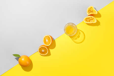 Miinimal orange juice flat lay. Fresh orange and glass of juice on trendy colors gray and yellow background. ... Creative breakfast top viewの写真素材