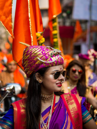 Mumbai, India - MARCH 18, 2018 : A beautiful indian female dressed in traditional attire driving a bike during a procession celebrating 'Gudhi Padwa' or the Maharashtrian new year in Mumbaiのeditorial素材