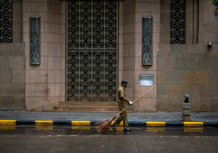 MUMBAI, INDIA - JUNE 24, 2018 : A male sweeper at work around streets of Ballard Estate, Mumbai