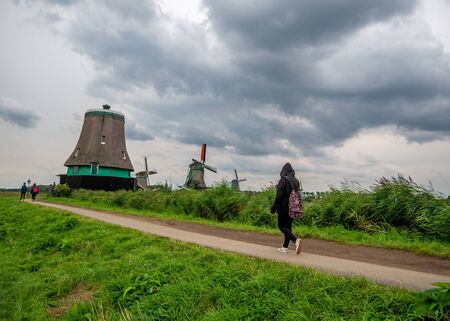 Zaanse Schans, Holland - August 26, 2018 : A tourist walking pass Traditional Dutch house in Zaanse Schans. The Zaanse Schans is a typically Dutch small village in Amsterdam, Netherlands.のeditorial素材