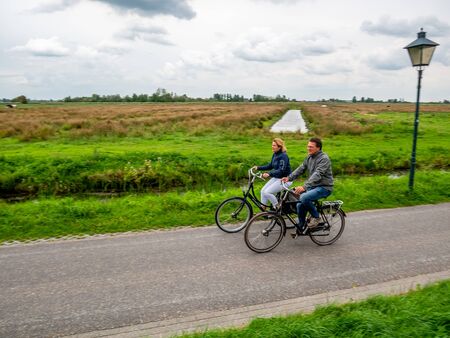 Zaanse Schans, Holland - August 26, 2018 : Couple cyclist on bike path in Zaanse Schans. The Zaanse Schans is a typically Dutch small village in Amsterdam, Netherlands.のeditorial素材