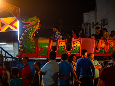 Mumbai, India - December 01, 2019: Indian family enjoying thrilling roller coaster ride at amusement park illuminated at nightのeditorial素材