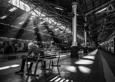 Mumbai, India - December 18, 2019 : Unidentified passengers sitting on a bench with early morning...