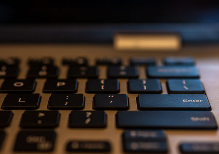 Closeup of laptop keyboard, Black keys on silver laptop. Enter key in focus.
