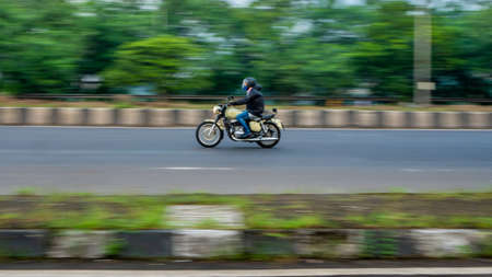 MUMBAI, INDIA - September 27, 2020 : People with a mask riding a motorbike on the streets of Mumbai exercising on a sunny day during the quarantine of the COVID-19 / coronavirus pandemicのeditorial素材