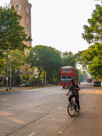 MUMBAI, INDIA - November 26, 2021 : Unidentified man riding a bicycle by wearing covid-19 mask and watching the mobile. Unsafe riding.のeditorial素材