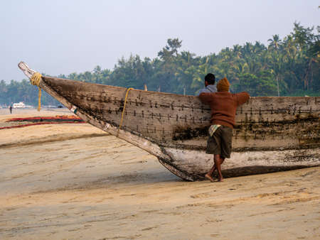 Malvan, India - December  20, 2021 : Indian fishermen with fishing boat at the seashore.のeditorial素材