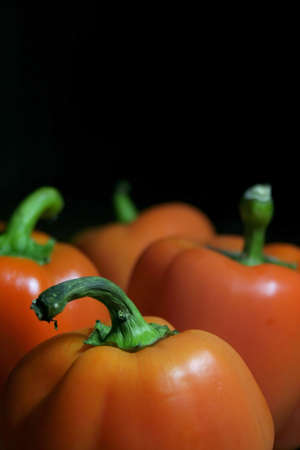 Fresh sweet orange bell peppers isolated against a black backgroundの写真素材