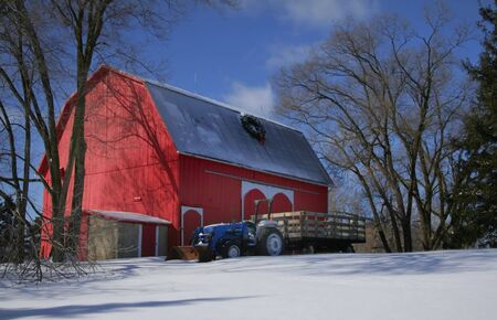 Blue tractor parked next to red barn in the farm の写真素材