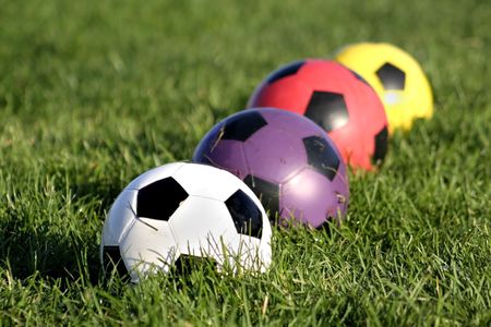 White purple red and yellow soccer balls in a rowの写真素材