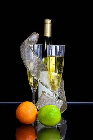 Two champagne glasses and bottle against black background の写真素材