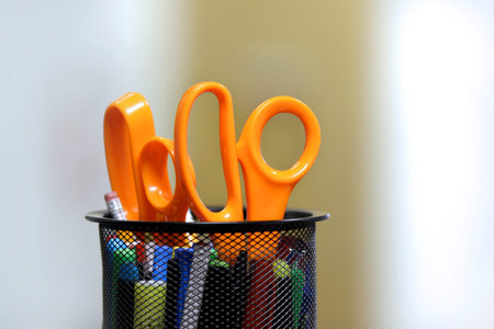 Orange scissors in pen holder with shallow depth of field